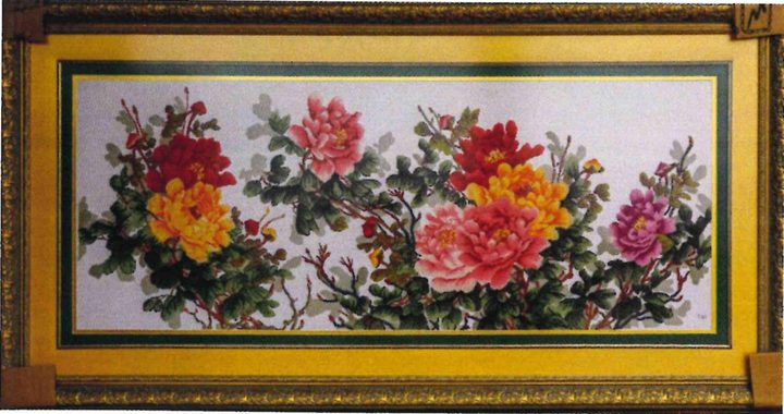 Long cross-stitch panel of peonies in red, pink, coral and yellow among green leaves on a pale ground, in a gold frame.