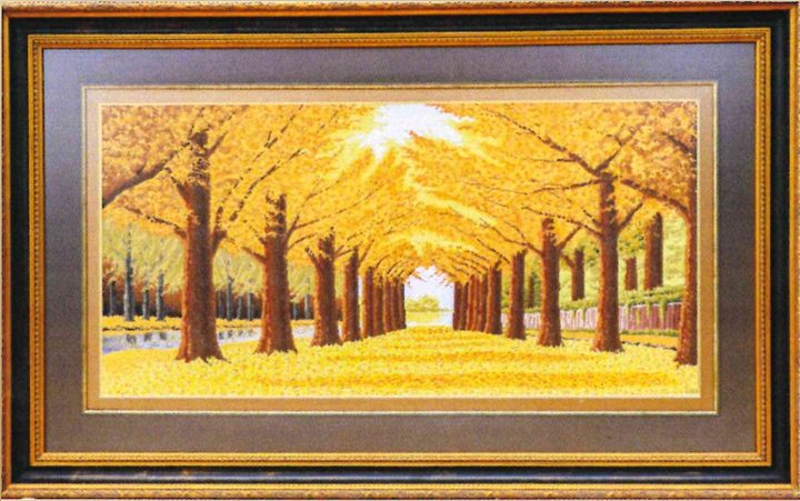 Cross-stitch artwork of an avenue of trees in bright yellow autumn leaves, a golden path running to the sun at the far end.
