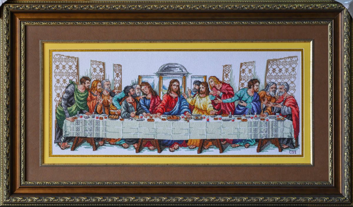 Framed cross stitch of The Last Supper in a dark carved frame.